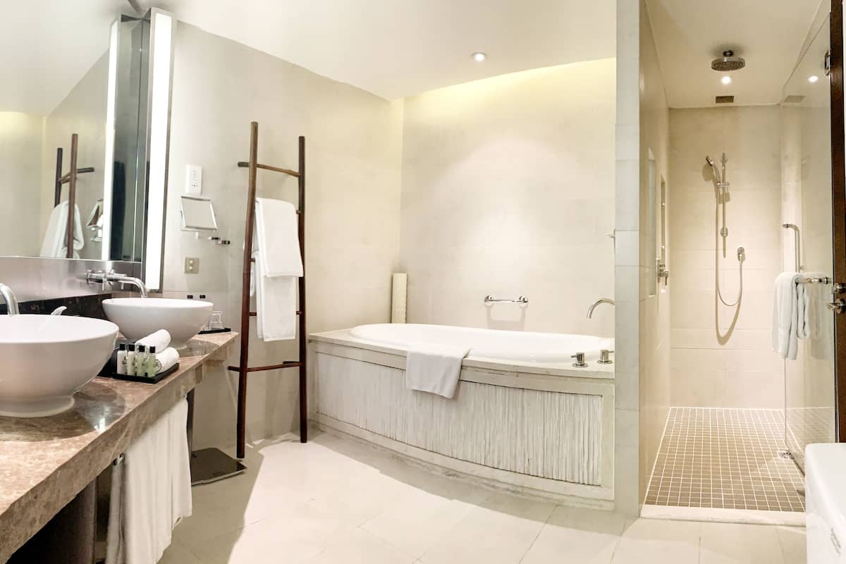 A modern bathroom with a large sink, a bathtub, and a walk-in shower.