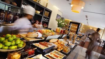 Buffet com diversos alimentos e um chefe preparando refeições.