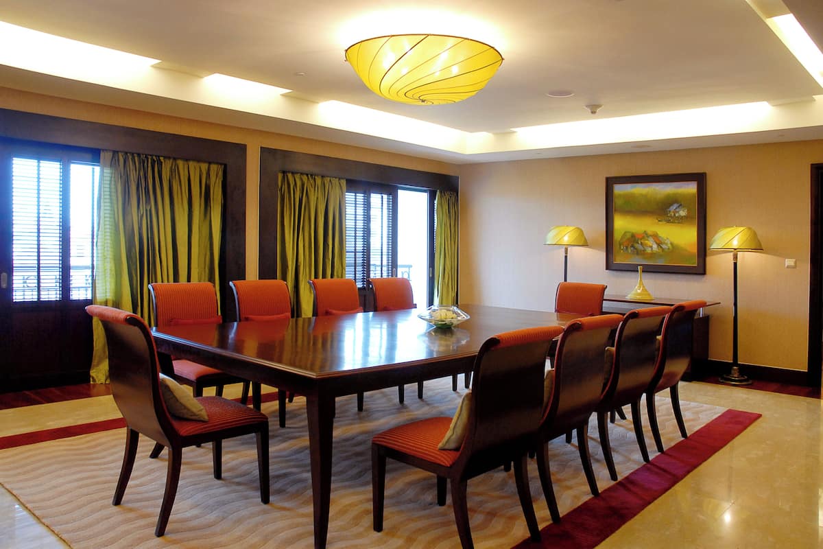 A conference room with a large table, chairs, a chandelier, and curtains.