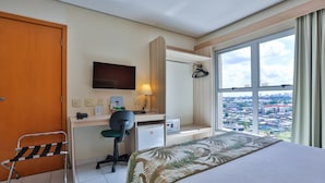 A hotel room with a bed, desk, chair, TV, and a window with a city view. - Sleep Inn Manaus (Manaus)