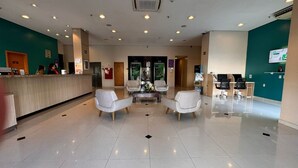 A hotel lobby with a reception desk, seating area, and a large window. - Sleep Inn Manaus (Manaus)