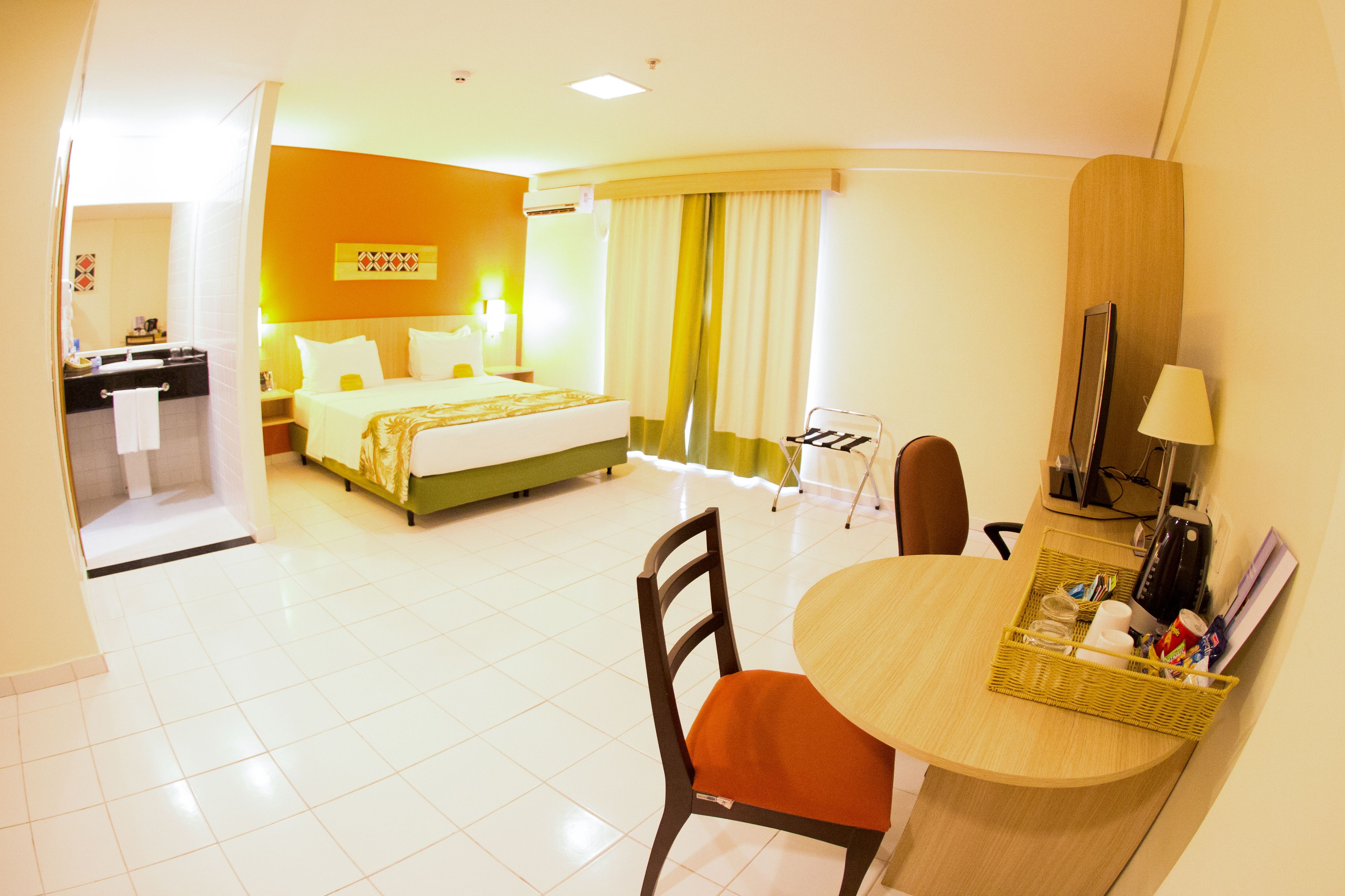 A hotel room with a bed, a desk, a chair, and a dining table.