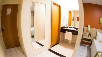 A hotel bathroom with a sink, mirror, and towel rack.