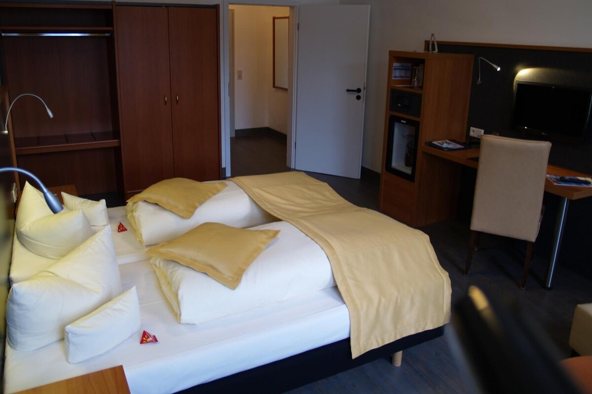 Una habitación de hotel con cama, escritorio, silla, armario y televisor.