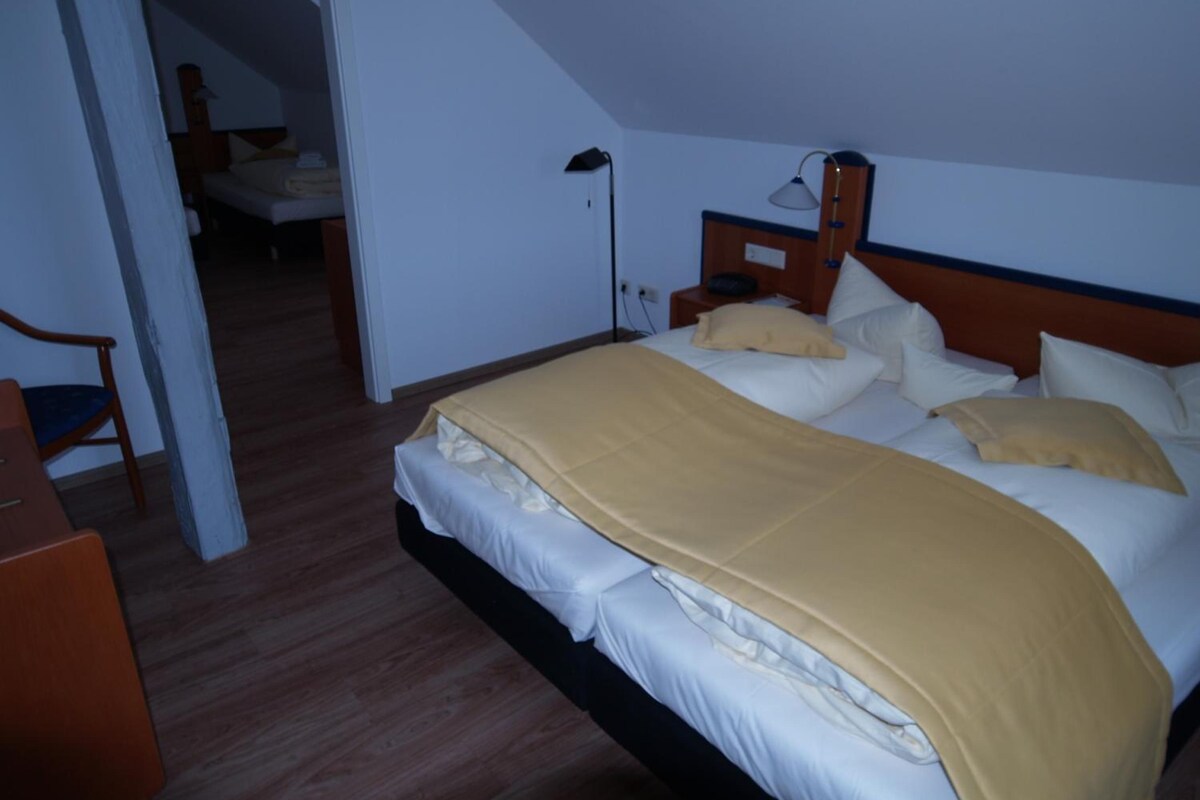 Una habitación de hotel con cama, mesita de noche, lámpara y una silla.