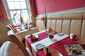 A dining area with a booth seating arrangement, a table set with plates, cutlery, and a fruit platter. - Goldene Krone (Clausthal-Zellerfeld)