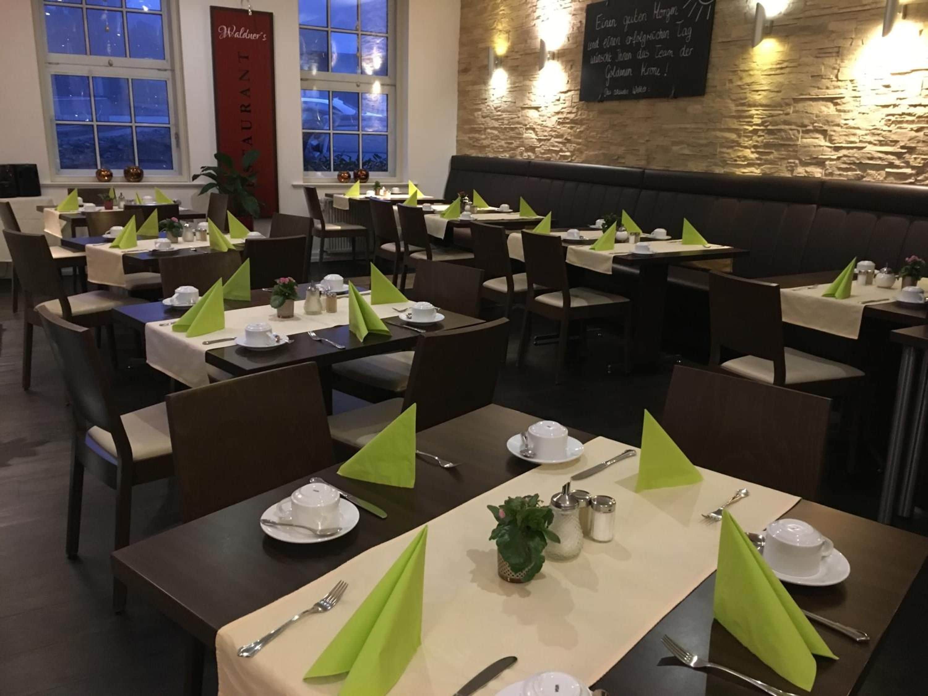 Ein Restaurant mit gedeckten Tischen, mit grünen Servietten und weißem Geschirr.