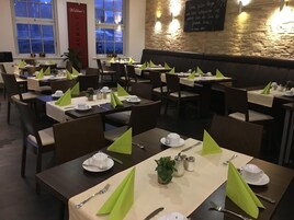 Un restaurante con mesas dispuestas para comer, con servilletas verdes y vajilla blanca.