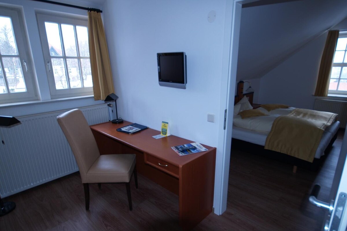 Una habitación con escritorio, silla, cama y televisión en la pared.