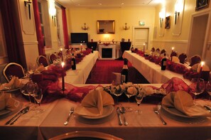 A formal dining room with long tables set for a meal, candles, and a fireplace. - Goldene Krone (Clausthal-Zellerfeld)