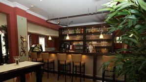 Uma área de bar com diversas opções de assento, balcão e prateleiras repletas de garrafas.