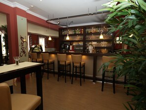 A bar area with multiple seating options, a bar counter, and shelves stocked with bottles. - Goldene Krone (Clausthal-Zellerfeld)