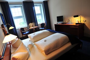 A hotel room with two beds, a desk, a chair, a lamp, and a TV. - Goldene Krone (Clausthal-Zellerfeld)
