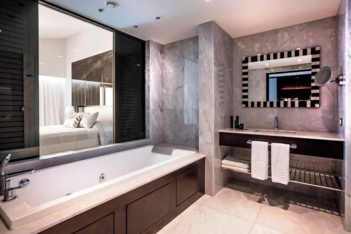 Un baño moderno con una bañera grande, un tocador con espejo y una zona de ducha.