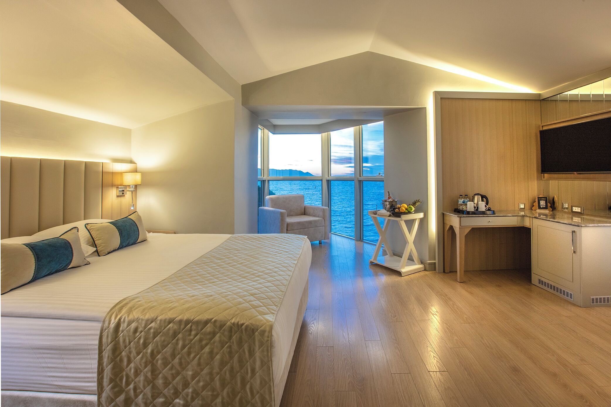Una habitación de hotel moderna con una cama grande, un escritorio y vistas al mar.
