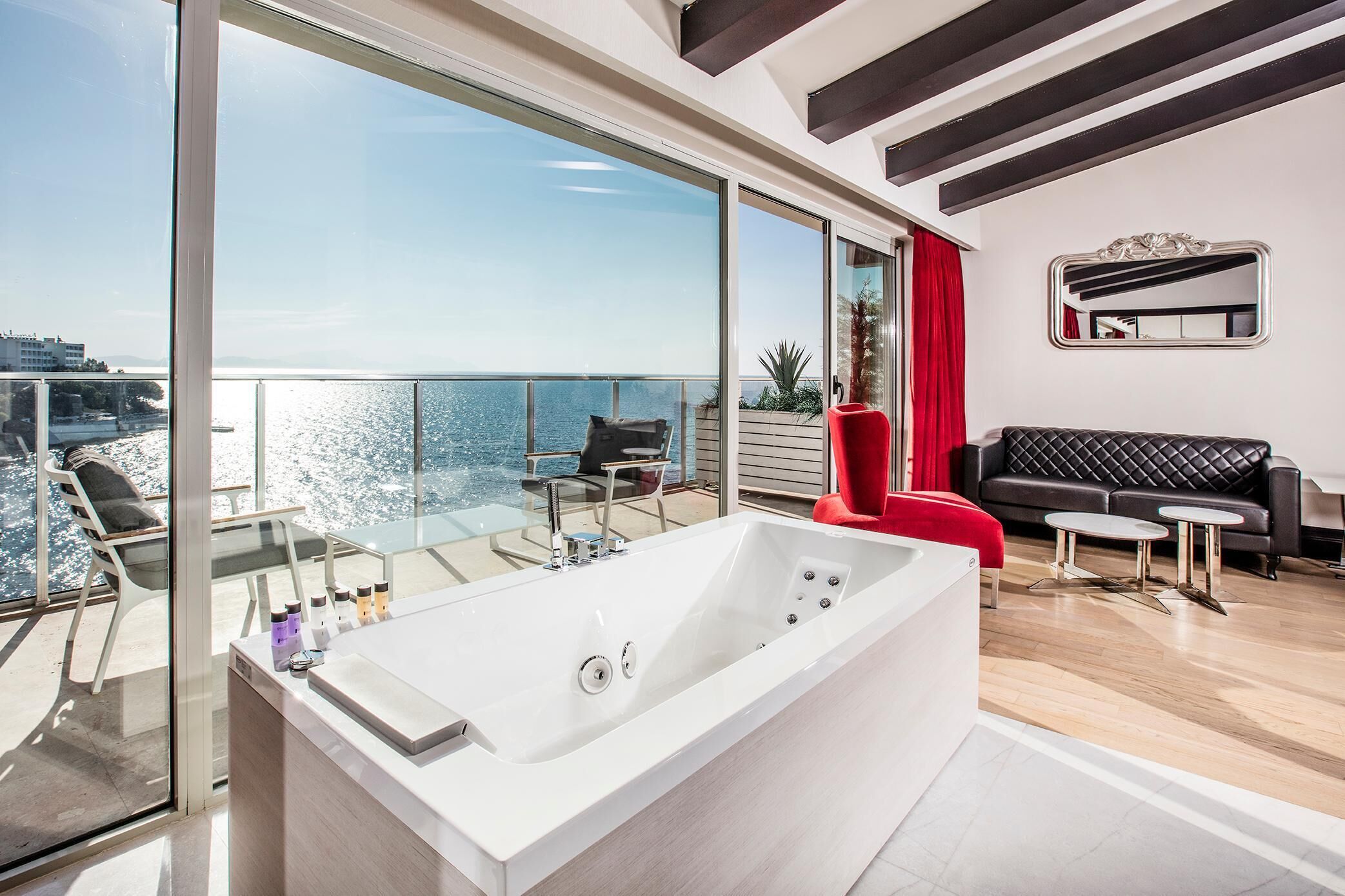 Un salon moderne doté d’une grande porte vitrée donnant sur un balcon qui offre une vue sur une étendue d’eau.