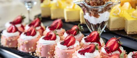 A variety of desserts including strawberry-topped cakes and a glass bowl with a layered dessert.