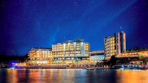 A waterfront hotel with multiple floors, balconies, and a pool area. - Charisma De Luxe Hotel (Kusadasi)
