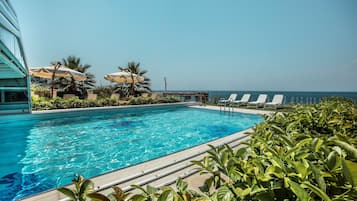 Una piscina techada, una piscina al aire libre, sombrillas