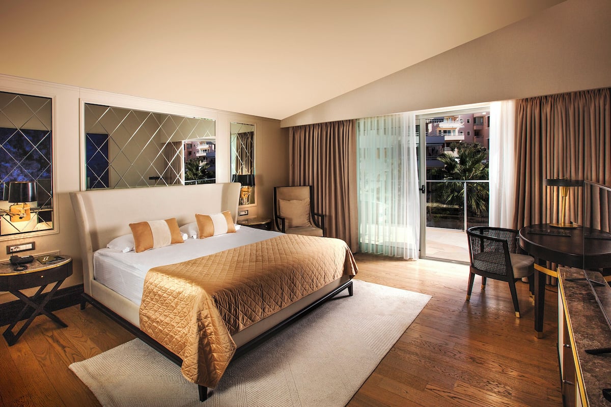 Habitación de hotel moderna con una cama grande, un rincón de comedor y vistas al exterior.