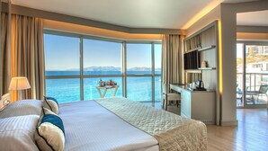 A hotel room with a large bed, a desk, and a view of the sea. - Charisma De Luxe Hotel (Kusadasi)