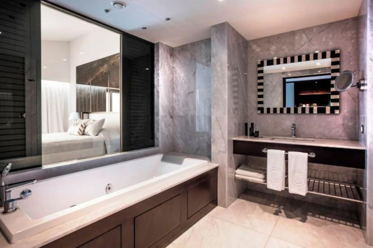 Un baño moderno con una bañera grande, un tocador con espejo y una zona de ducha.