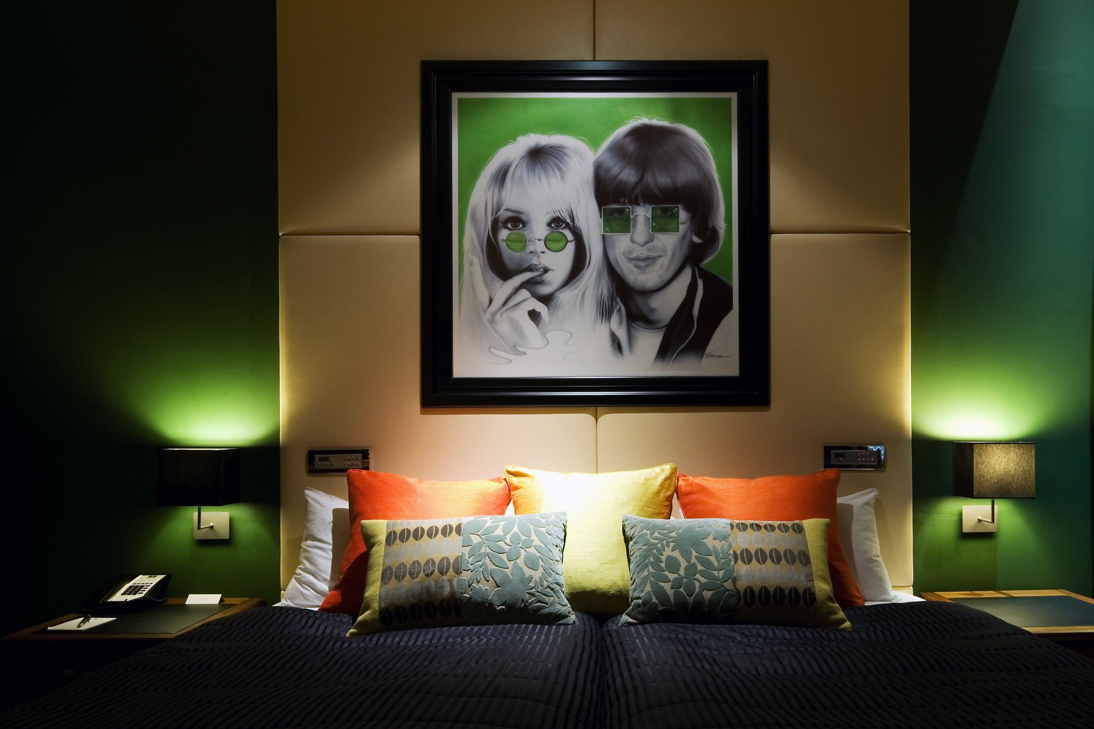 A hotel room with a bed, pillows, a framed picture on the wall, and bedside lamps.