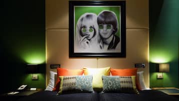 A hotel room with a bed, pillows, a framed picture on the wall, and bedside lamps.