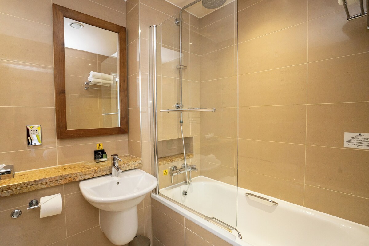 A bathroom with a sink, mirror, shower, and bathtub.
