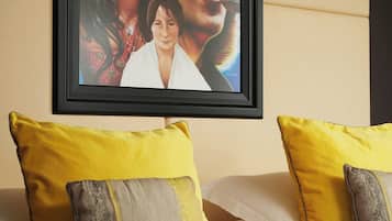 Una cama con almohadas amarillas y grises, un cuadro enmarcado en la pared y un cabecero de madera.