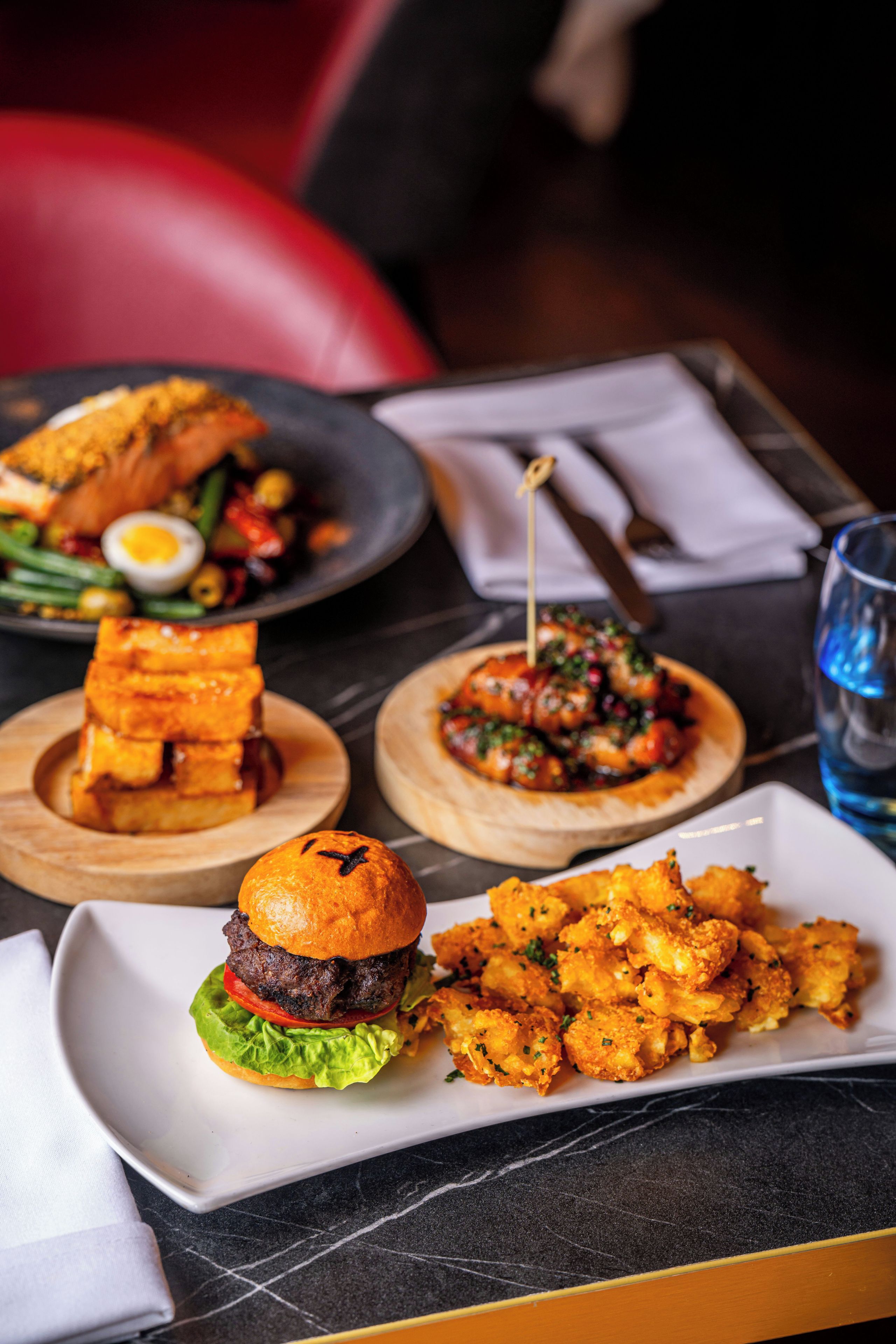 A dining table with various dishes including a burger, fries, and a salad.