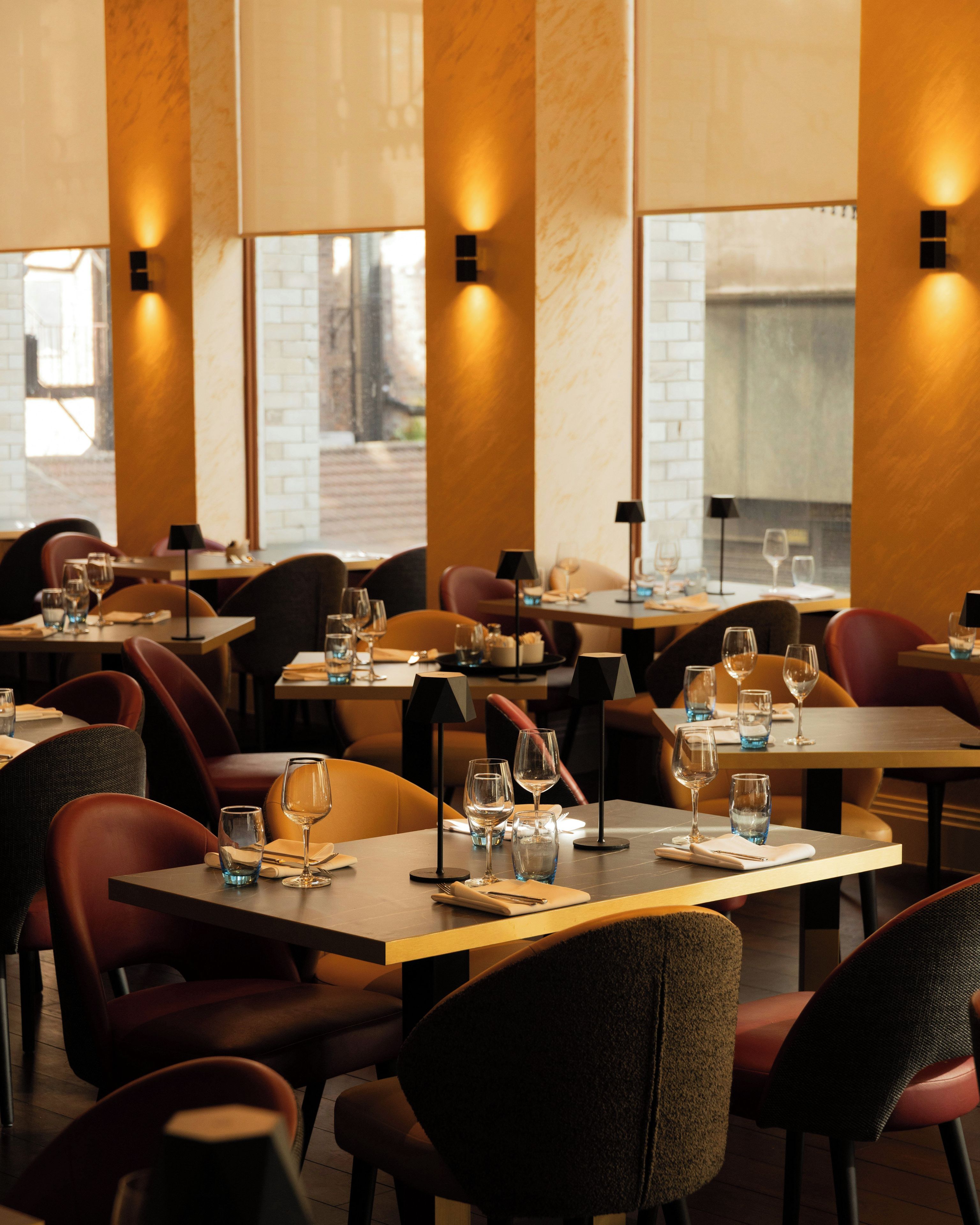 A restaurant interior with tables set for dining, chairs, and ambient lighting.