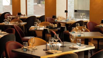A restaurant interior with tables set for dining, chairs, and ambient lighting.