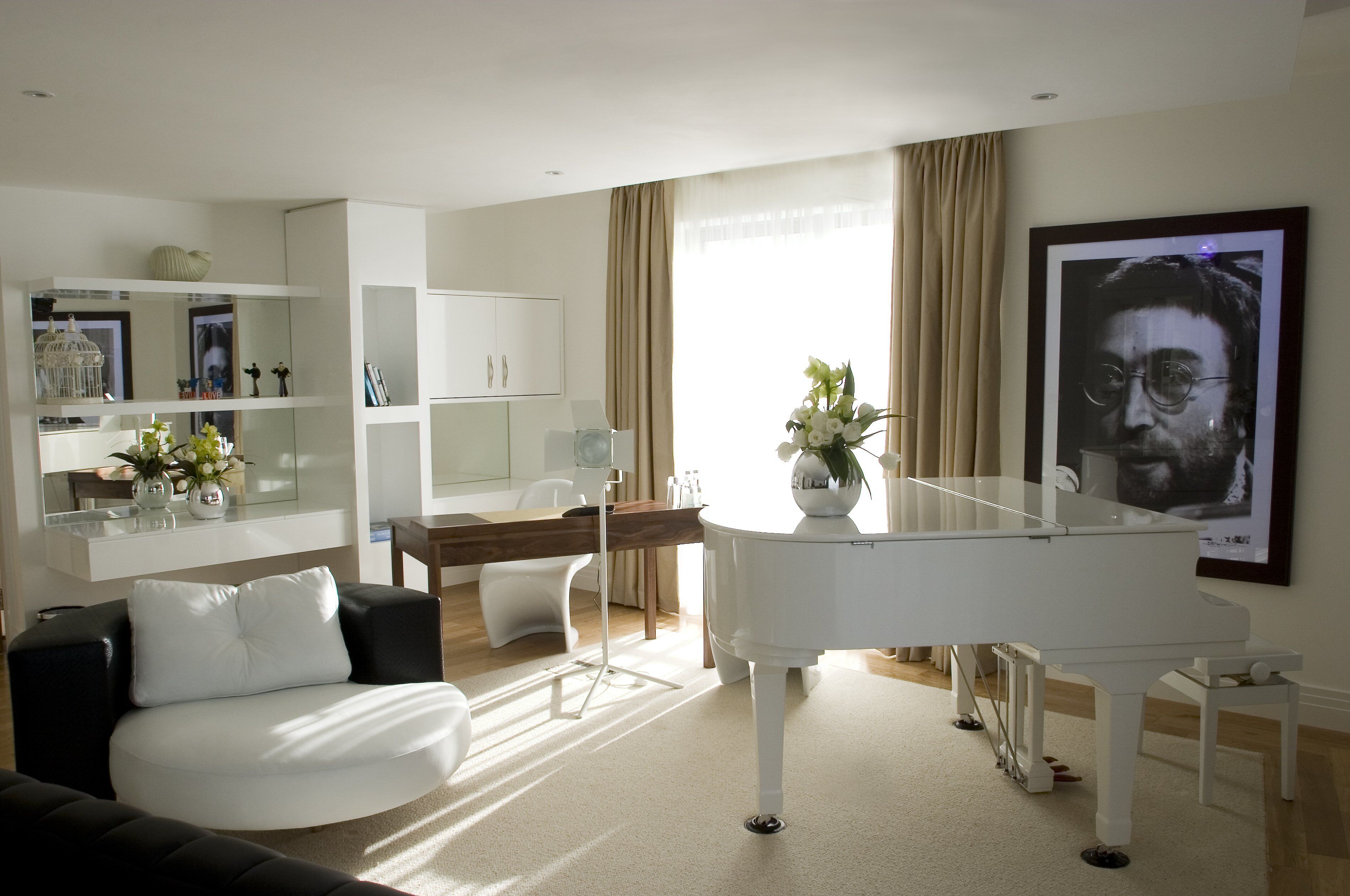 A modern living room with a white grand piano, a white sofa, and a dining area with a wooden table and chairs.
