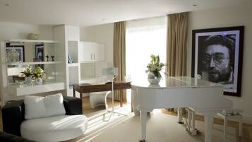 A modern living room with a white grand piano, a white sofa, and a dining area with a wooden table and chairs.