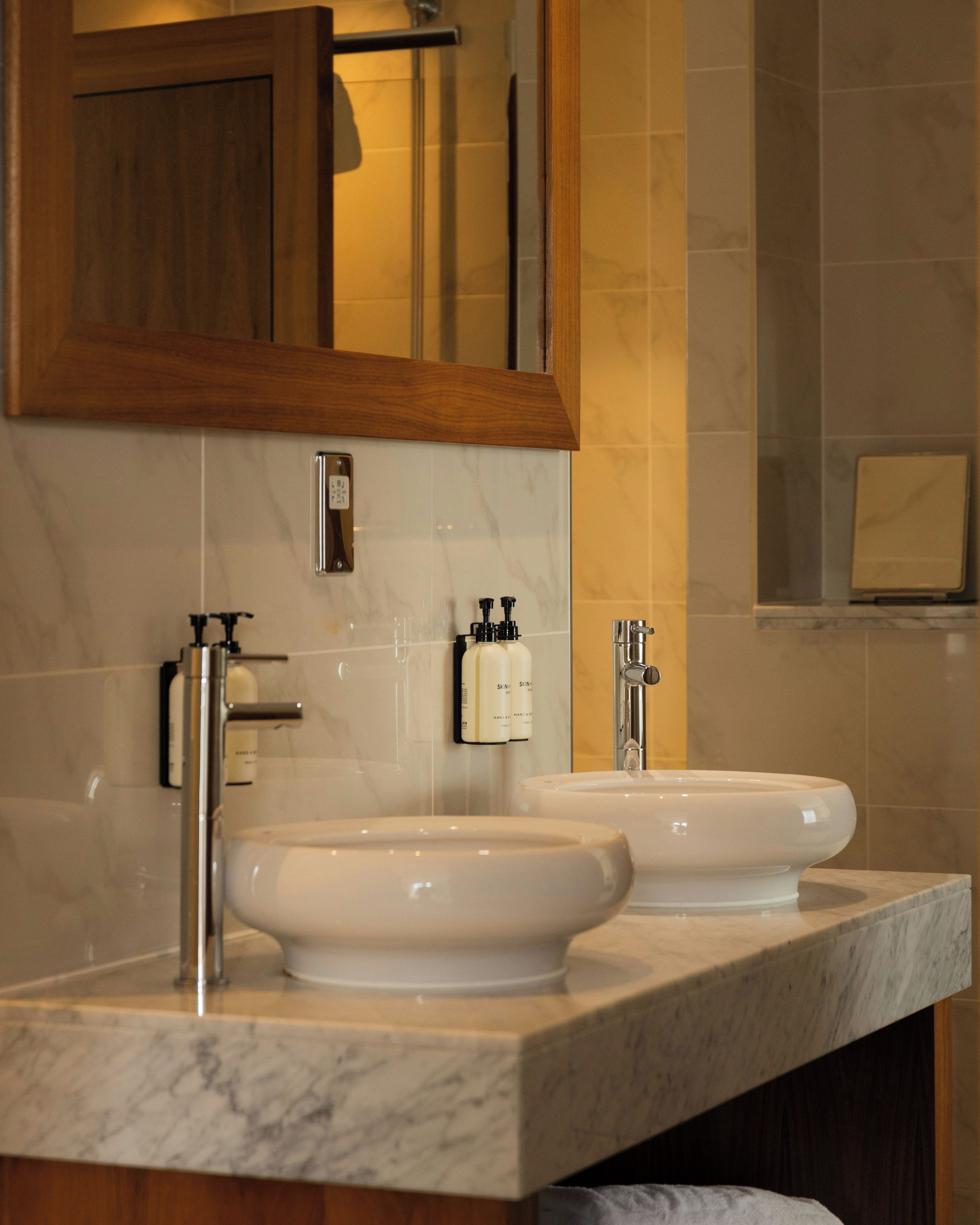 A bathroom with two sinks, a mirror, and a towel rack.