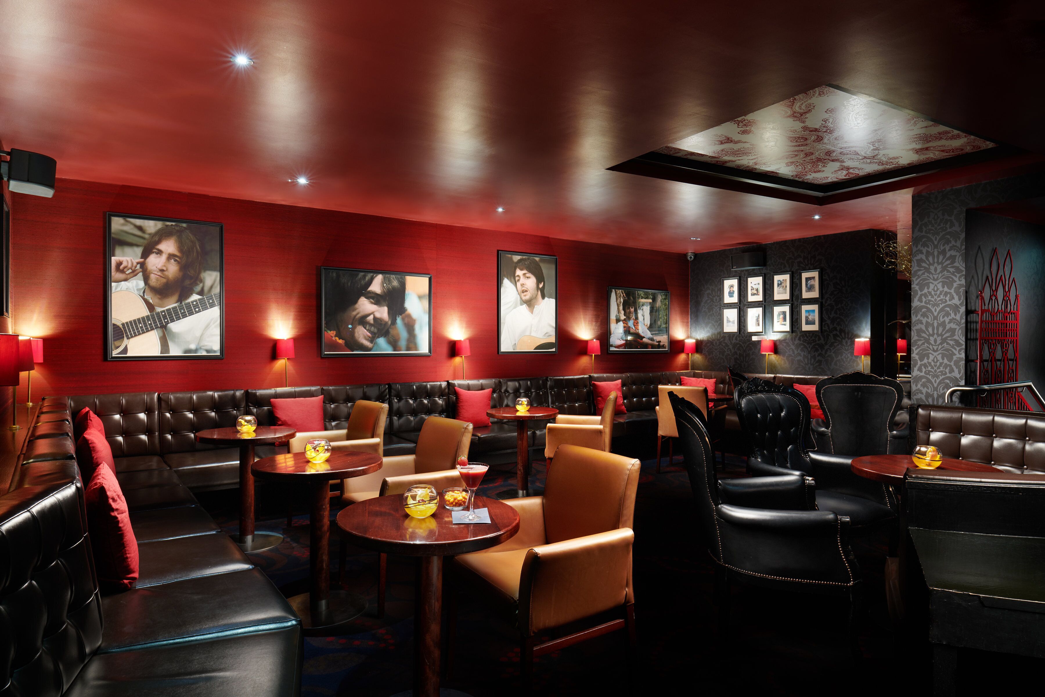 A dimly lit restaurant with leather booths, tables, and framed pictures on the walls.