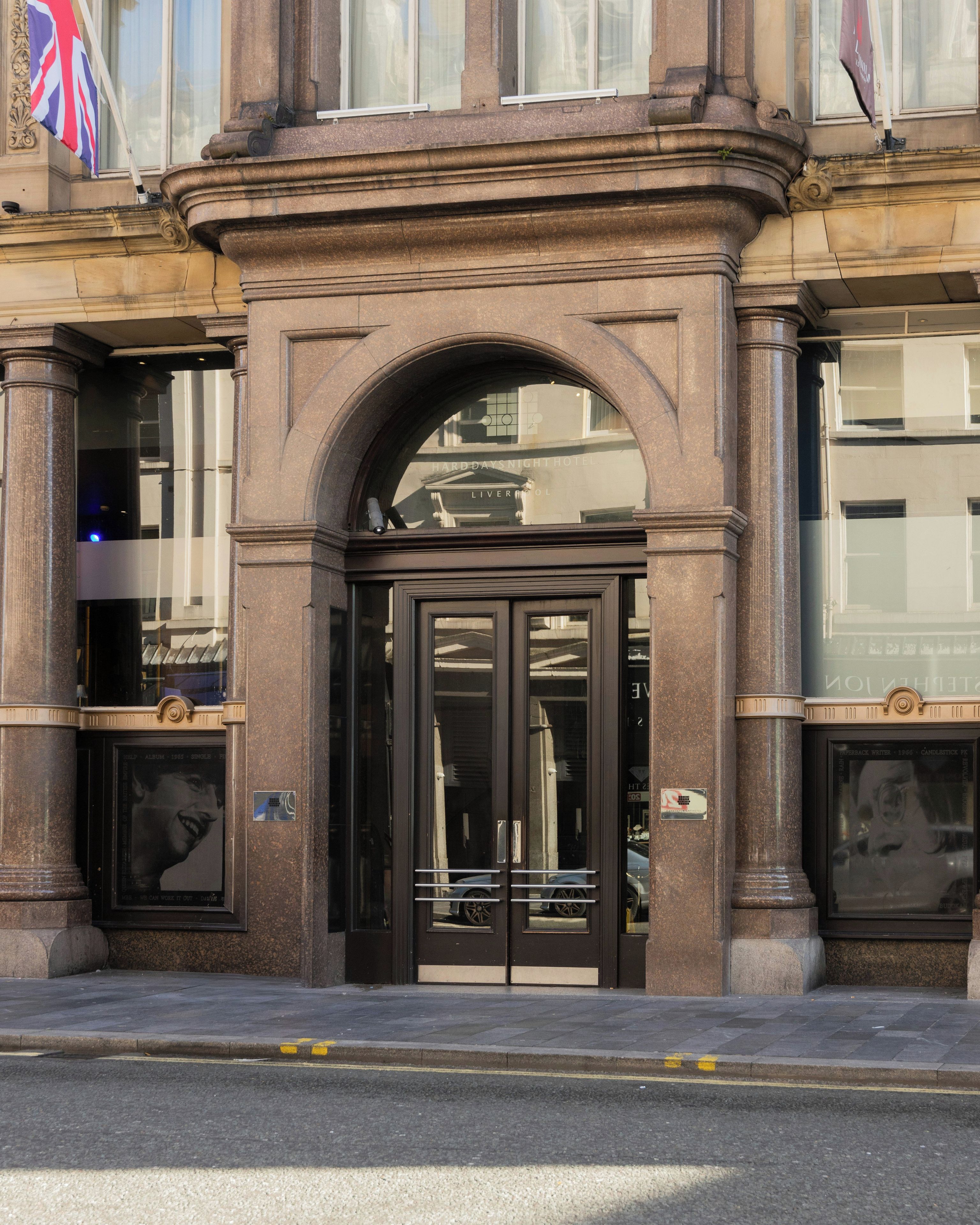 A building entrance with a black door, large windows, and a British flag.