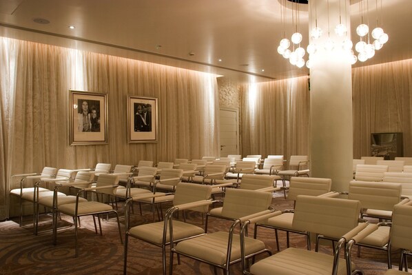 A conference room with rows of beige chairs, a chandelier, and framed pictures on the walls. - Hard Days Night Hotel Liverpool (Liverpool)