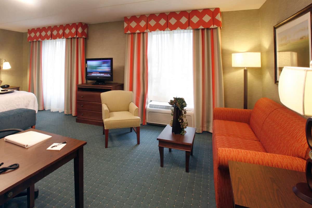 Une chambre d’hôtel comprenant un lit, un bureau avec un téléphone, une chaise, un canapé, une télévision et une lampe.
