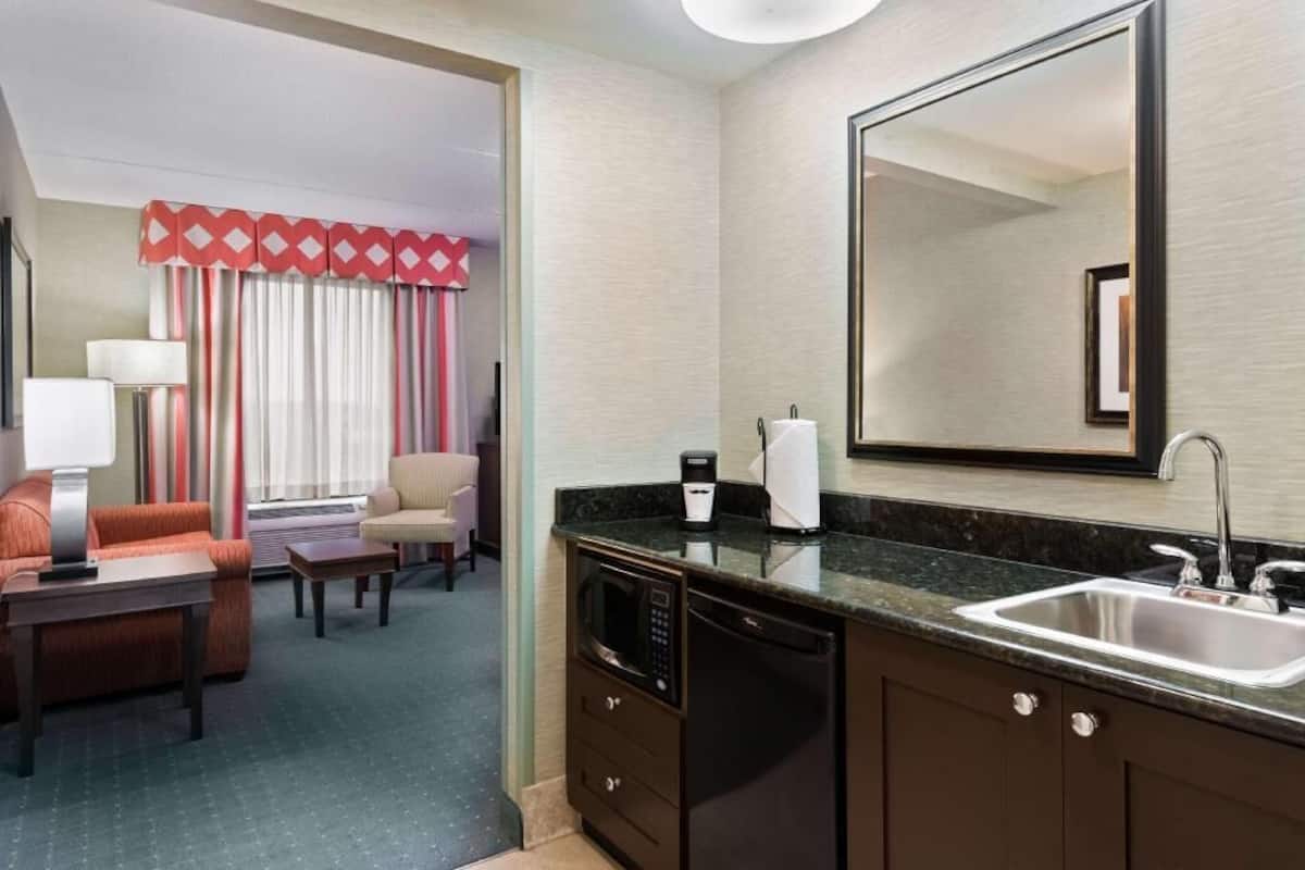 Une chambre d’hôtel équipée d’une kitchenette, d’un coin repas, d’un grand miroir et offrant une vue sur la pièce.
