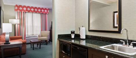 A hotel room with a kitchenette, a dining area, and a living space.