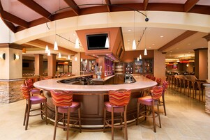 A bar area with a round counter, multiple bar stools, and overhead lighting.