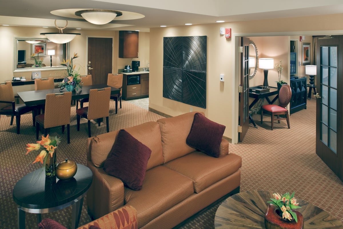 A hotel room with a living area, dining area, and kitchenette.