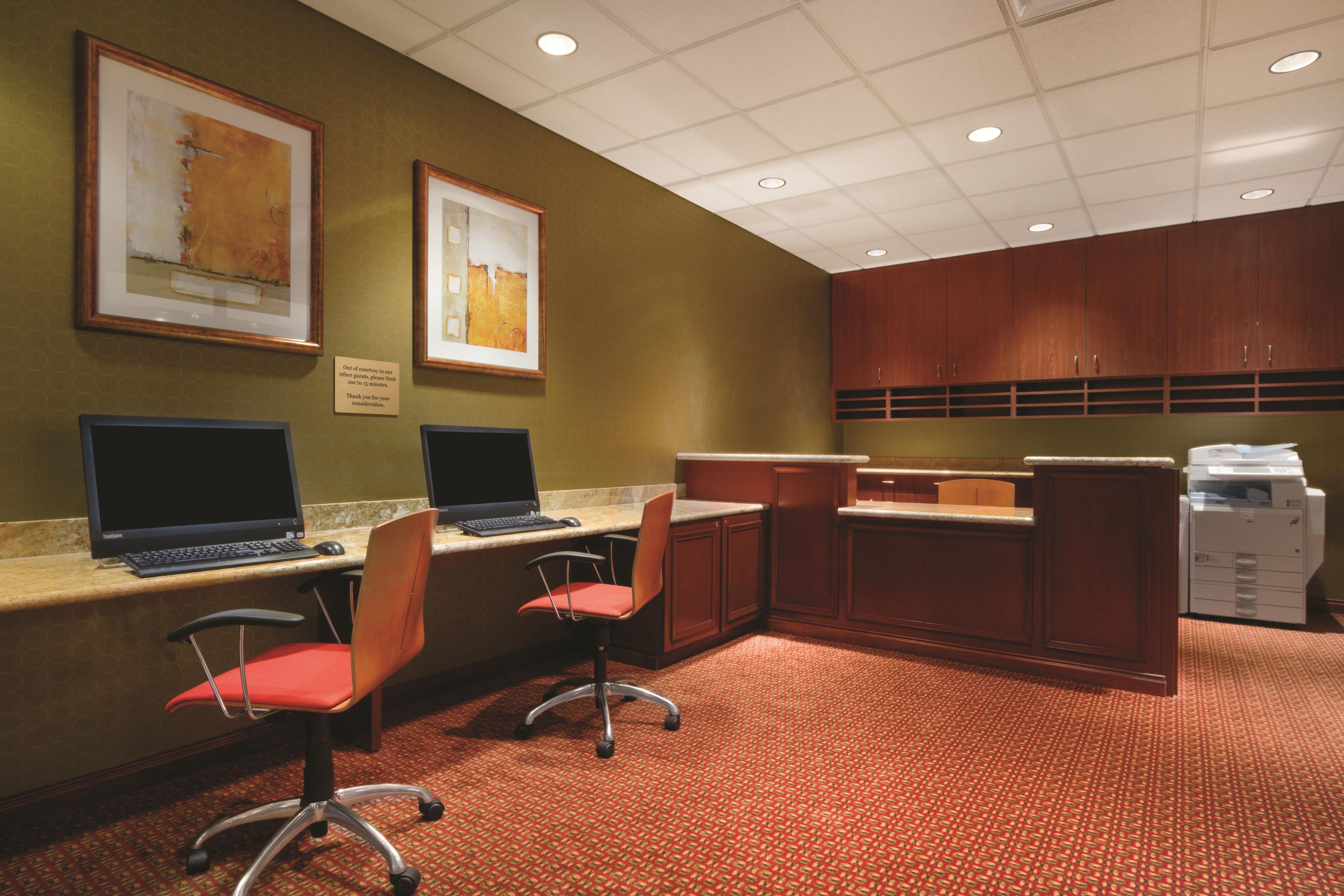 A conference room with two desks, chairs, a reception desk, and a printer.