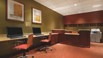 A conference room with two desks, chairs, a reception desk, and a printer.