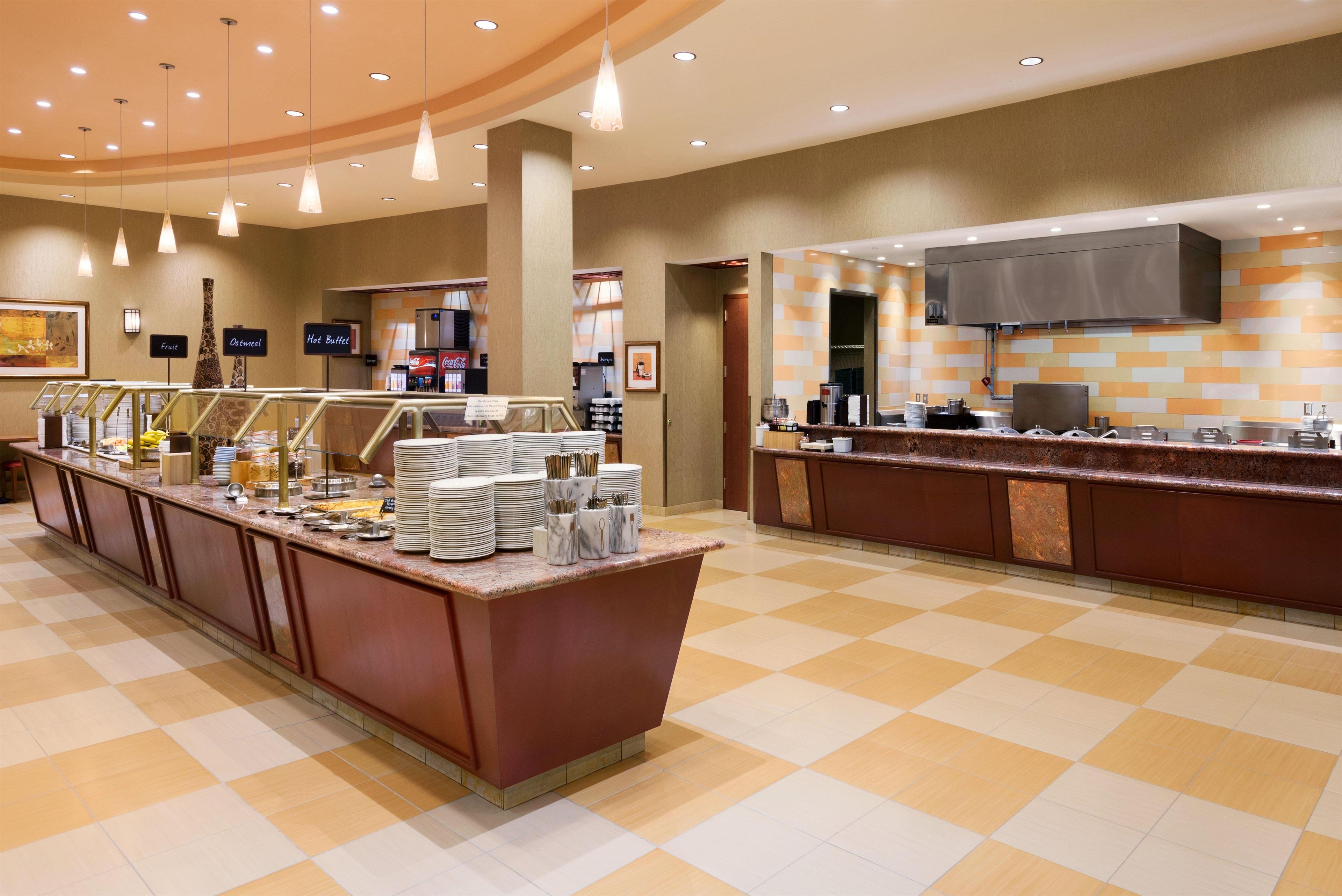 A hotel breakfast area with a buffet setup, including a variety of food items and a coffee station.