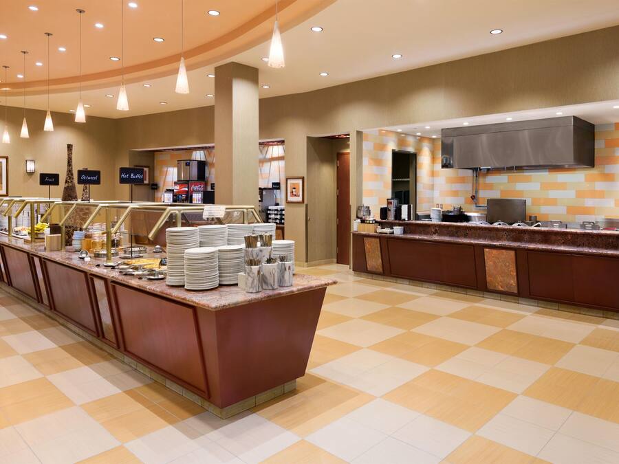 A hotel breakfast area with a buffet setup, including a variety of food items and a coffee station.