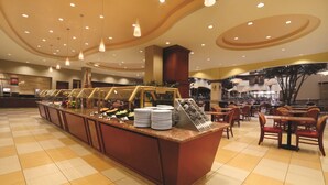 Un espace buffet doté d’un îlot central, de plusieurs types d’aménagements pour s’asseoir et d’un plafond pourvu d’un éclairage encastré.
