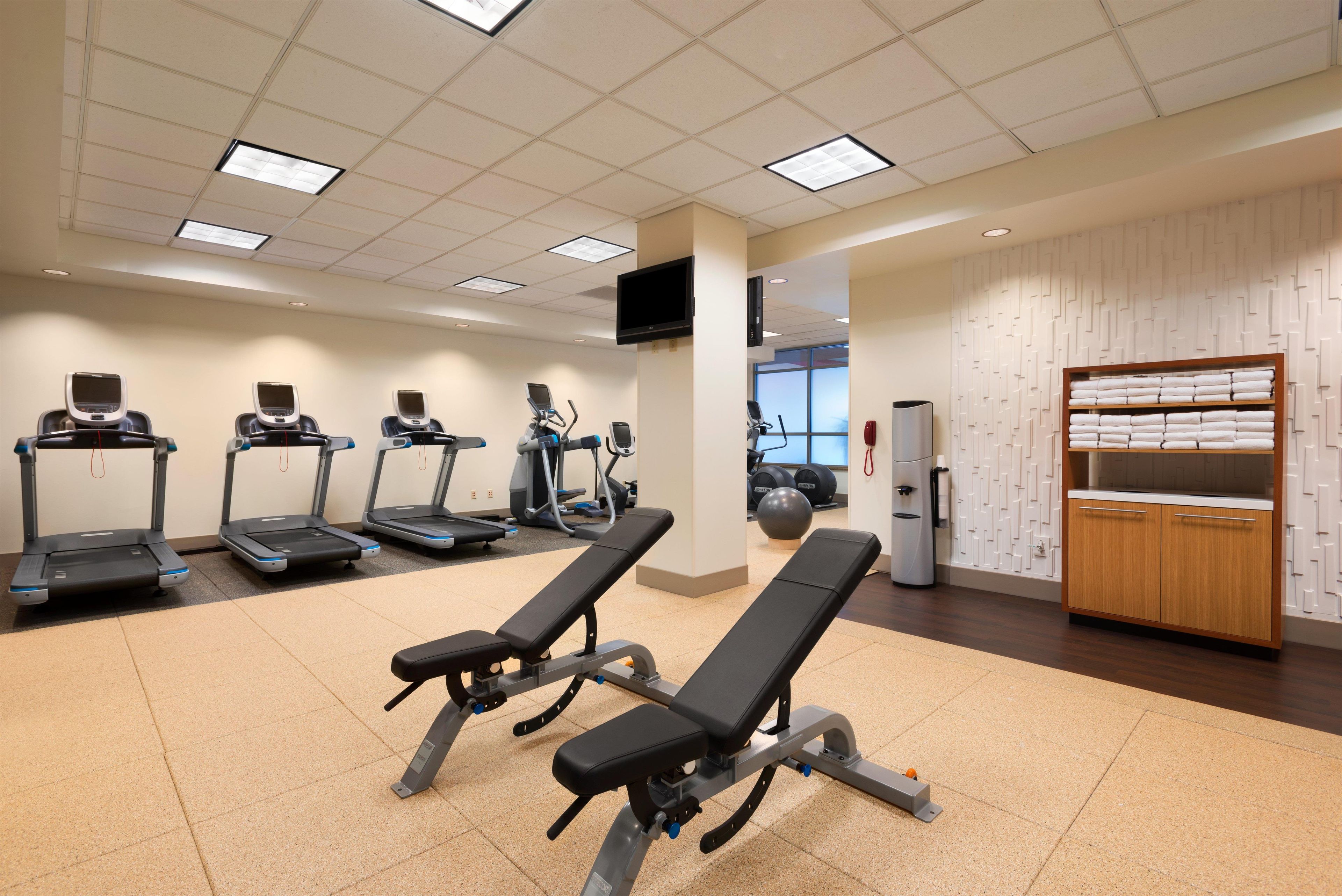 A gym with treadmills, elliptical machines, and weight benches.